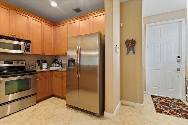 kitchen featuring visible vents, light stone counters, appliances with stainless steel finishes, light tile patterned floors, and baseboards