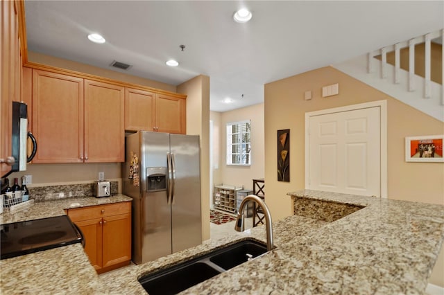 kitchen with visible vents, light stone counters, recessed lighting, stainless steel refrigerator with ice dispenser, and a sink