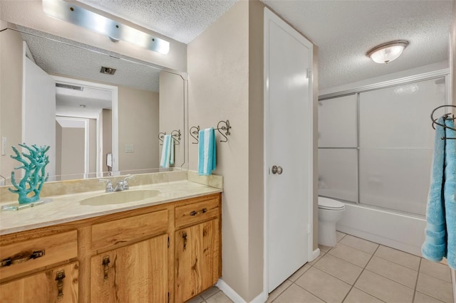 135 Cedar Dunes Dr, New Smyrna Beach, FL 32169 - full bath featuring tile patterned flooring, vanity, toilet, shower / bath combination with glass door, and a textured ceiling