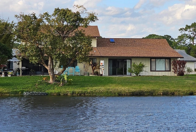 view of front facade featuring board and batten siding, a front lawn, and a water view