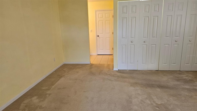 unfurnished bedroom featuring tile patterned floors, baseboards, a closet, and carpet floors