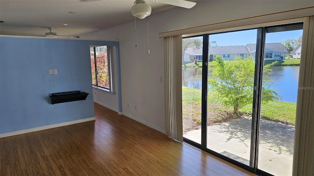 spare room featuring baseboards, a water view, a ceiling fan, and wood finished floors