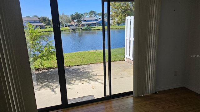 doorway featuring a residential view, wood finished floors, baseboards, and a water view