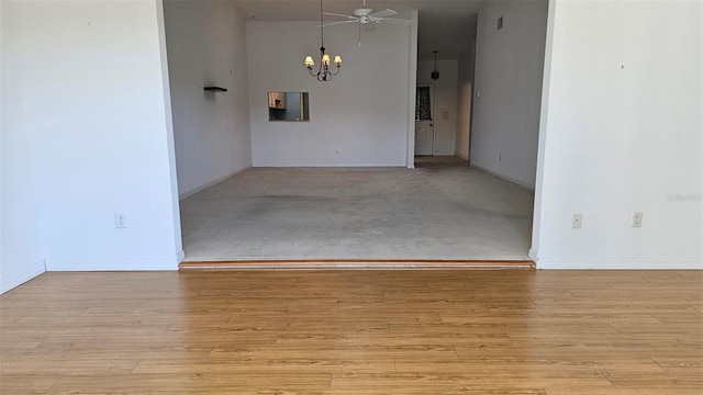 spare room featuring wood finished floors, baseboards, and a chandelier