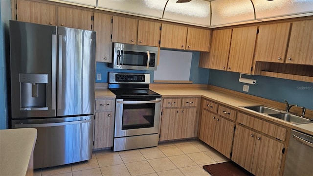 kitchen featuring light tile patterned floors, stainless steel appliances, light countertops, and a sink