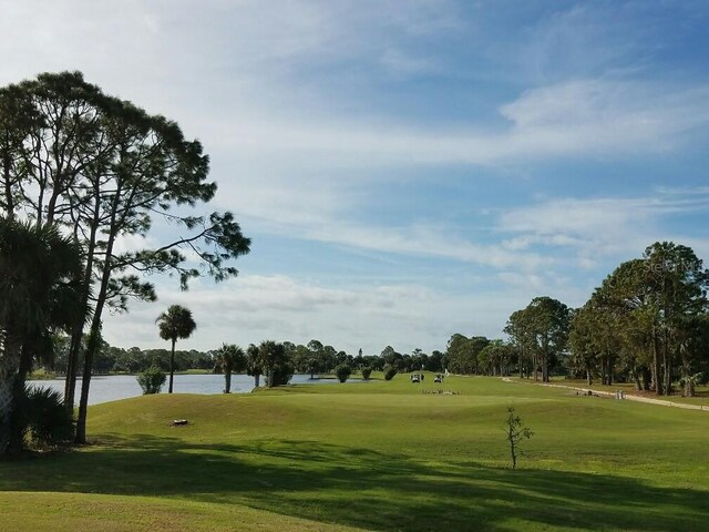 view of property's community with a lawn, golf course view, and a water view