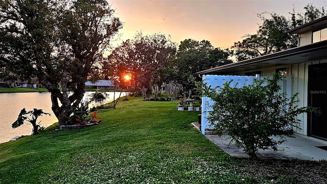 yard at dusk featuring a water view