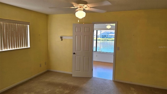 spare room featuring carpet flooring, a textured ceiling, baseboards, and ceiling fan