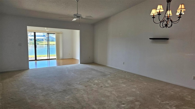 empty room with carpet flooring, ceiling fan with notable chandelier, and a textured ceiling