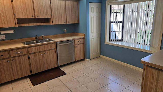 kitchen with light tile patterned flooring, a sink, light countertops, and stainless steel dishwasher