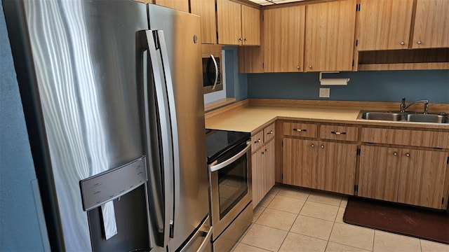 kitchen with light tile patterned floors, stainless steel appliances, light countertops, and a sink