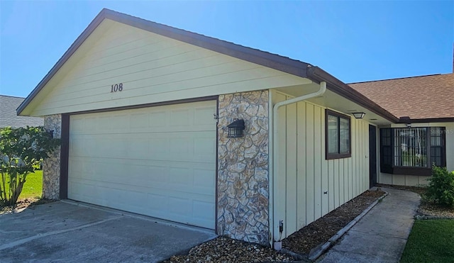 view of side of property featuring a garage and stone siding