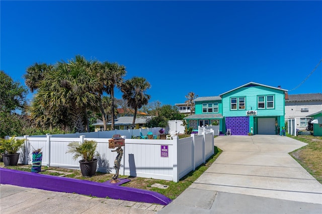 view of front facade with a garage, driveway, and a fenced front yard