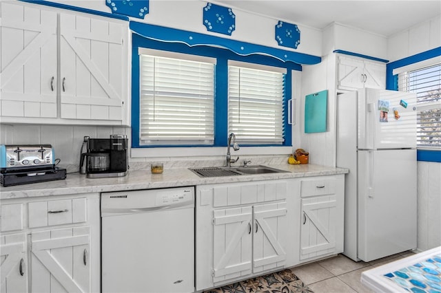 kitchen with a sink, white appliances, light tile patterned flooring, and white cabinets