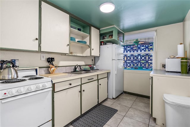 kitchen with white appliances, light tile patterned floors, open shelves, a sink, and light countertops