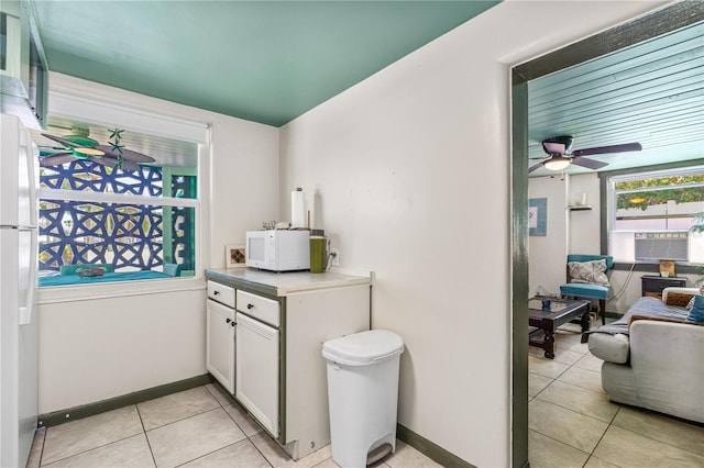 kitchen with open floor plan, white cabinetry, white appliances, light tile patterned floors, and baseboards