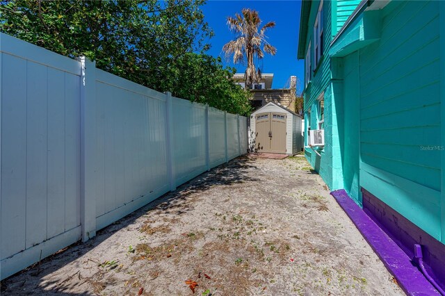 view of yard with a storage shed, cooling unit, an outbuilding, and fence