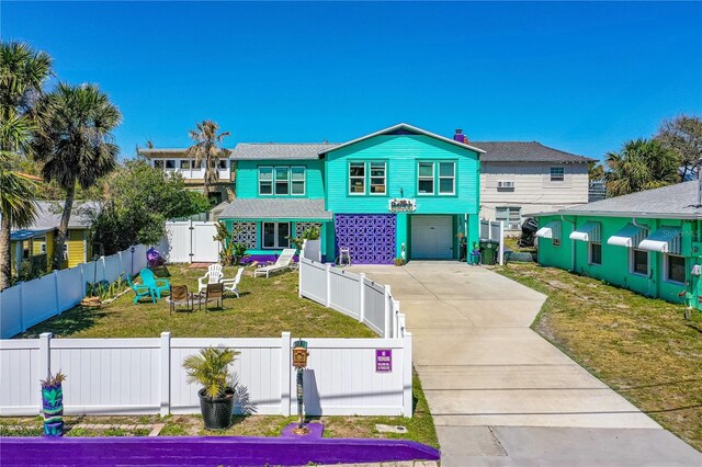 view of front of home with a front yard, a gate, driveway, a garage, and a fenced front yard