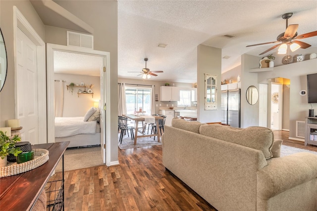 living room featuring visible vents, lofted ceiling, a textured ceiling, and dark wood-style flooring