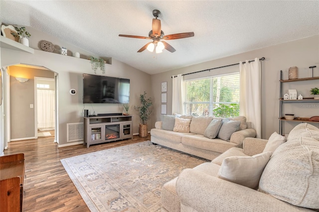 living area with visible vents, a textured ceiling, wood finished floors, and vaulted ceiling