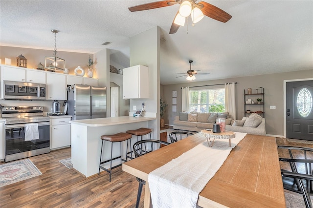 dining space with lofted ceiling, wood finished floors, visible vents, and a textured ceiling