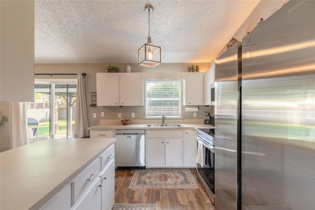 kitchen featuring a sink, dark wood-type flooring, appliances with stainless steel finishes, white cabinetry, and a wealth of natural light