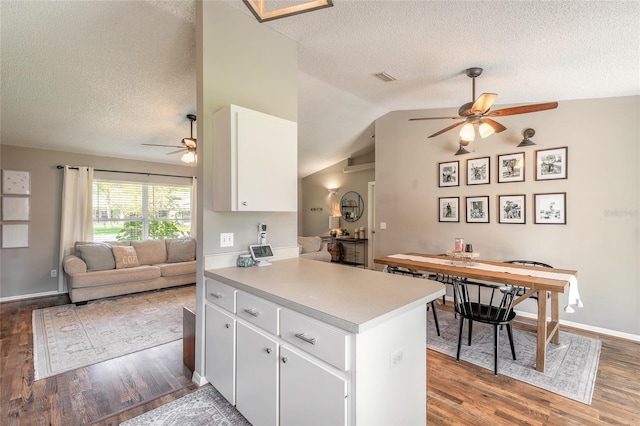 kitchen with wood finished floors, open floor plan, white cabinetry, a peninsula, and vaulted ceiling