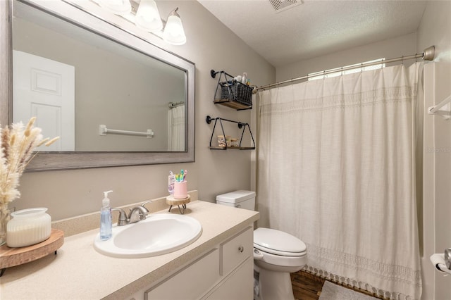 bathroom featuring curtained shower, a textured ceiling, toilet, and vanity