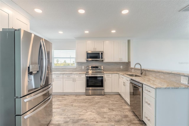 kitchen featuring visible vents, a sink, stainless steel appliances, a peninsula, and decorative backsplash