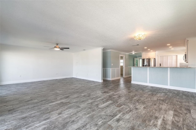 unfurnished living room with a ceiling fan, baseboards, dark wood finished floors, ornamental molding, and a textured ceiling