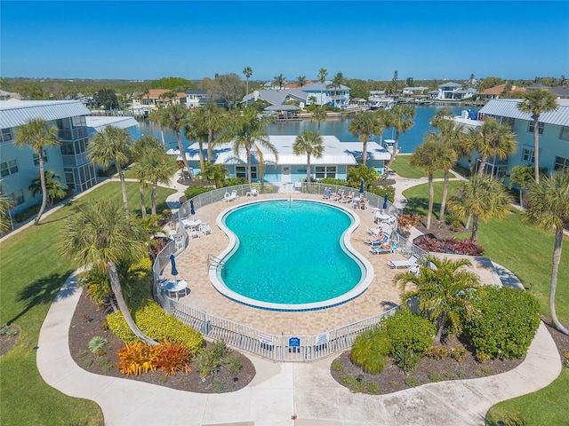 pool featuring a patio area, a water view, and fence