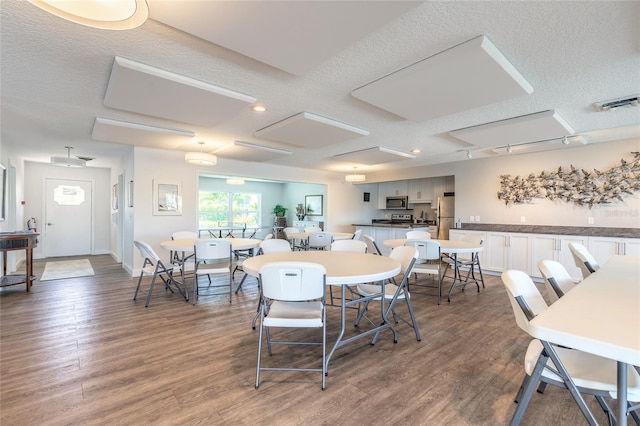 dining space featuring visible vents, baseboards, a textured ceiling, and wood finished floors