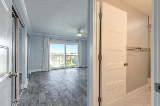 corridor with baseboards, a textured ceiling, and wood finished floors