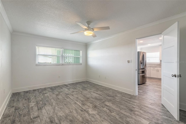 unfurnished room featuring ornamental molding, a textured ceiling, wood finished floors, baseboards, and ceiling fan