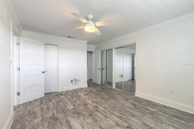 unfurnished bedroom featuring ornamental molding, two closets, and wood finished floors