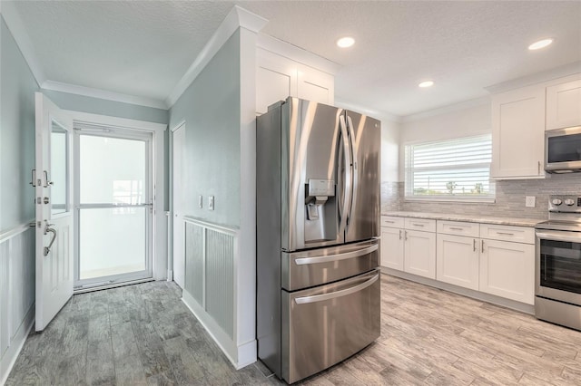 kitchen featuring stainless steel appliances, light wood-style flooring, and crown molding