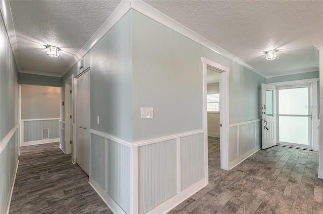 hallway with wainscoting, a textured ceiling, wood finished floors, and crown molding