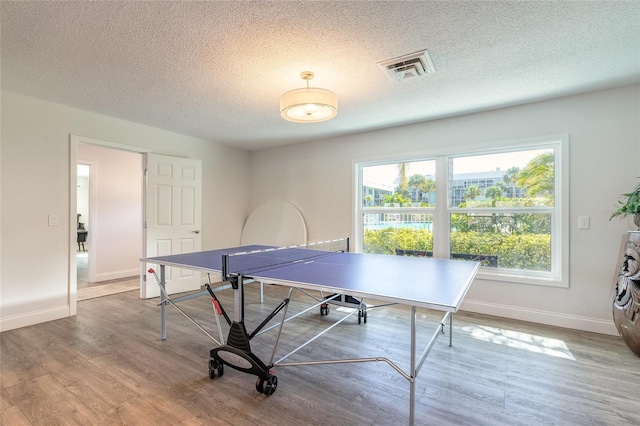 rec room featuring visible vents, baseboards, a textured ceiling, and wood finished floors