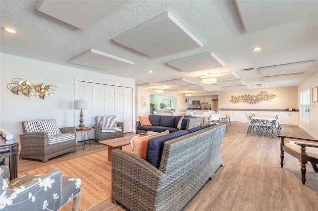 living room featuring visible vents, attic access, light wood-type flooring, recessed lighting, and a textured ceiling