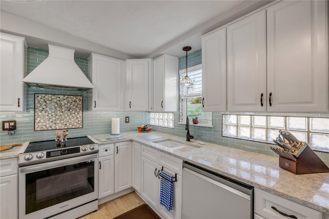 kitchen featuring a sink, backsplash, white cabinetry, appliances with stainless steel finishes, and custom exhaust hood