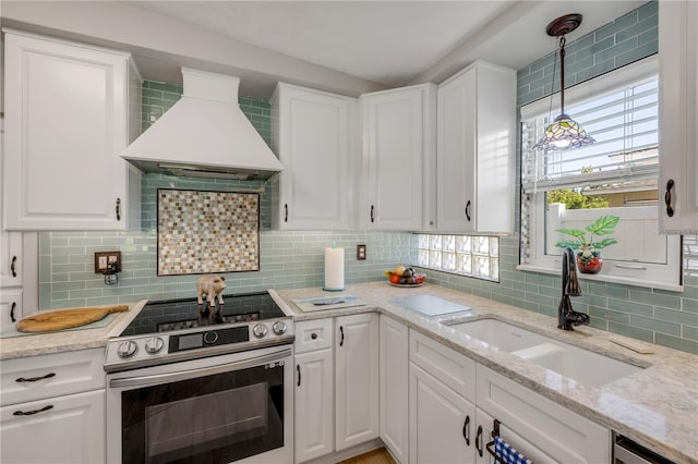 kitchen featuring custom range hood, decorative backsplash, white cabinets, stainless steel appliances, and a sink