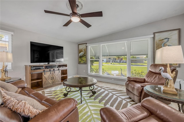 living area with lofted ceiling, plenty of natural light, wood finished floors, and ceiling fan