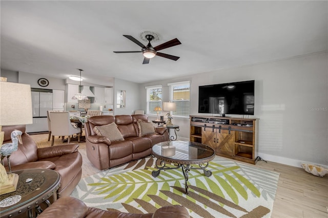 living area with baseboards, a ceiling fan, and light wood-style floors