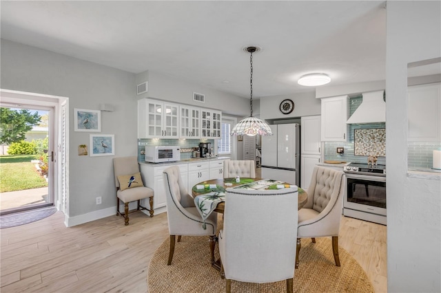 dining space featuring baseboards, visible vents, and light wood-type flooring