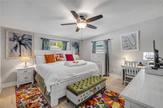 bedroom with light wood finished floors, a ceiling fan, and baseboards