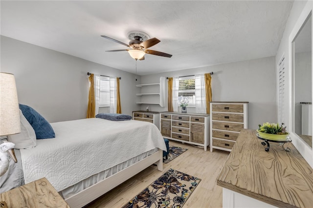 bedroom with multiple windows, light wood-style floors, and ceiling fan