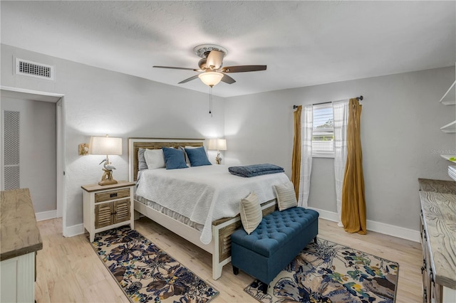 bedroom featuring visible vents, light wood-style flooring, baseboards, and ceiling fan