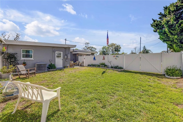 view of yard featuring a fenced backyard, central AC, and a gate