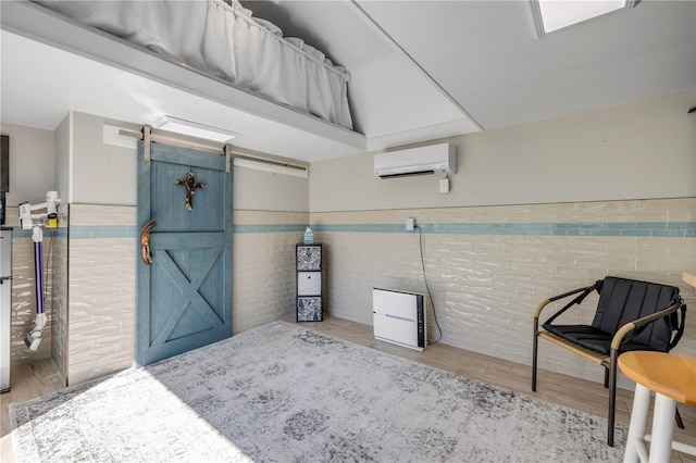 interior space featuring a barn door, wood finished floors, wainscoting, and a wall mounted AC