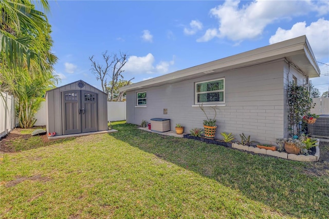 rear view of house featuring cooling unit, a yard, a fenced backyard, an outdoor structure, and a storage unit